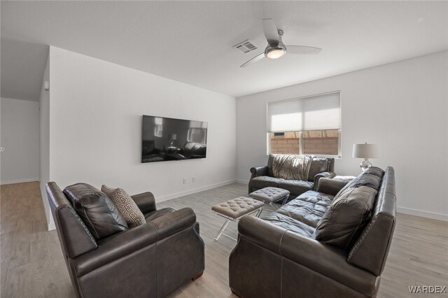 living area with baseboards, light wood finished floors, visible vents, and a ceiling fan