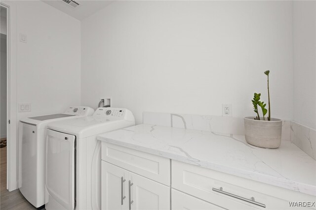 laundry area with visible vents, light wood-style flooring, washer and clothes dryer, and cabinet space