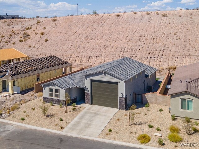 view of front of house with a garage, stone siding, concrete driveway, and stucco siding