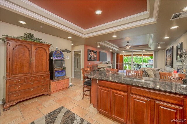 231 Moser Ave Unit G, Bullhead City, AZ 86429 - kitchen featuring dark stone counters, a raised ceiling, ornamental molding, and a breakfast bar