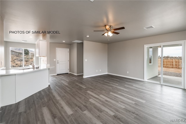 unfurnished living room with a sink, a wealth of natural light, dark wood-style floors, and visible vents