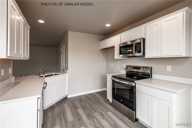 kitchen featuring white cabinetry, stainless steel appliances, light wood-style flooring, and a sink
