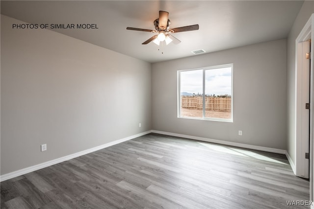 unfurnished room with a ceiling fan, baseboards, visible vents, and wood finished floors