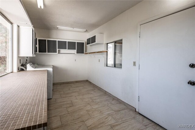 kitchen with white cabinetry, open shelves, light countertops, and washing machine and clothes dryer