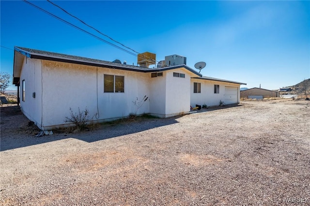 rear view of property featuring an attached garage and central AC unit