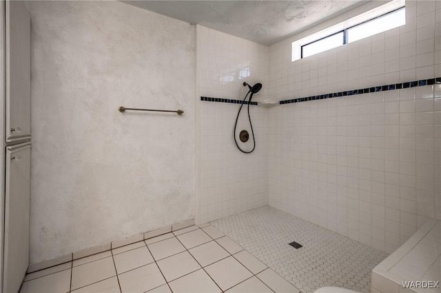 full bath with a textured wall, a tile shower, and tile patterned floors