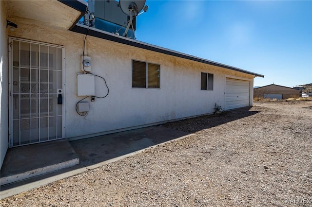 view of side of property with driveway, an attached garage, and stucco siding