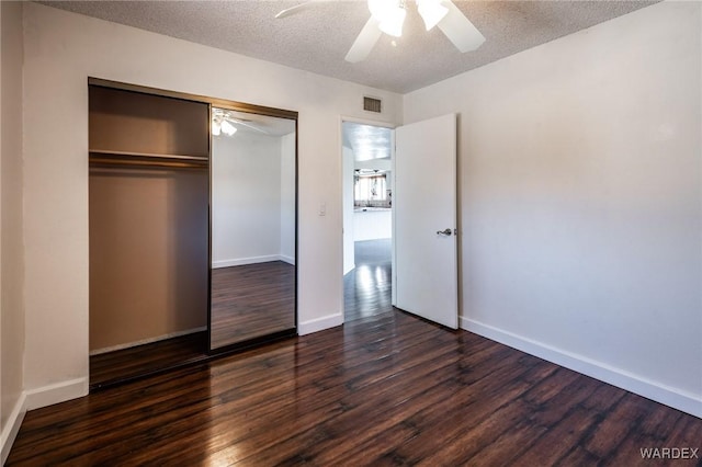 unfurnished bedroom featuring baseboards, a textured ceiling, visible vents, and dark wood-style flooring