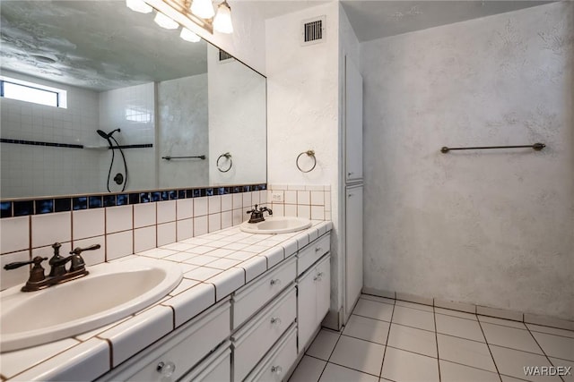 bathroom featuring visible vents, a sink, decorative backsplash, and double vanity