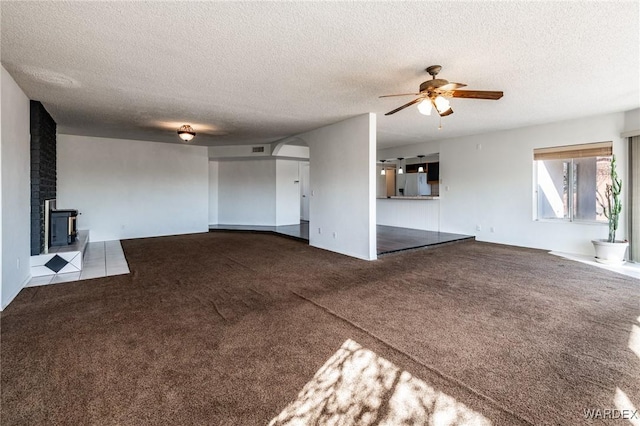 unfurnished living room with light carpet, visible vents, a textured ceiling, and a ceiling fan