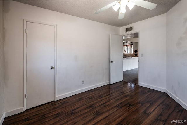 unfurnished room featuring visible vents, baseboards, dark wood-style floors, ceiling fan, and a textured ceiling