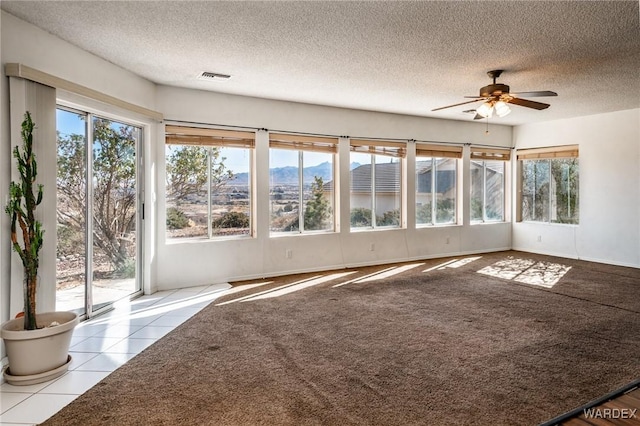 unfurnished sunroom with ceiling fan, visible vents, and a mountain view