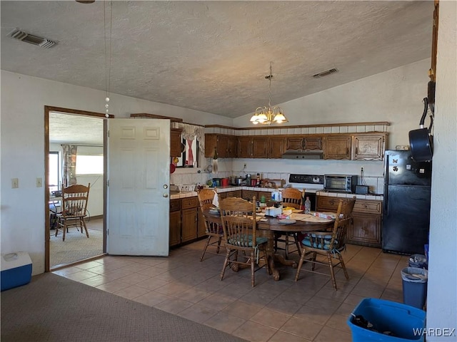 dining area featuring an inviting chandelier, vaulted ceiling, visible vents, and a textured ceiling