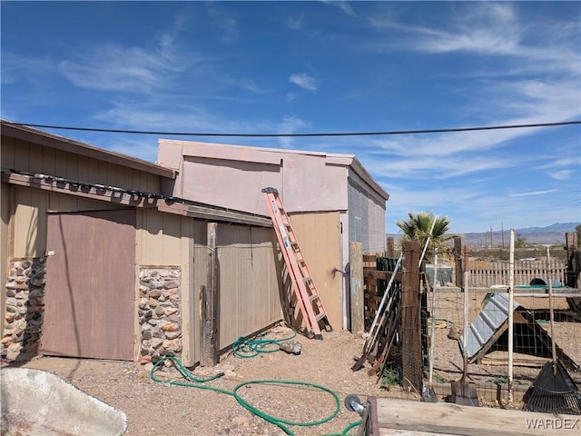 view of side of home with fence and a mountain view