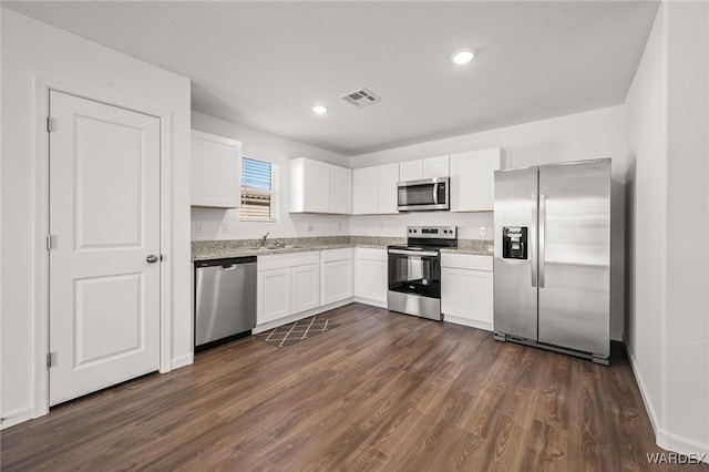 kitchen featuring white cabinets, visible vents, stainless steel appliances, and dark wood-type flooring