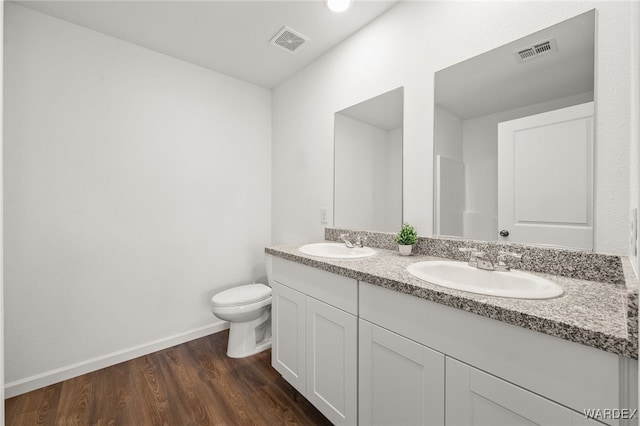 bathroom with toilet, visible vents, a sink, and wood finished floors