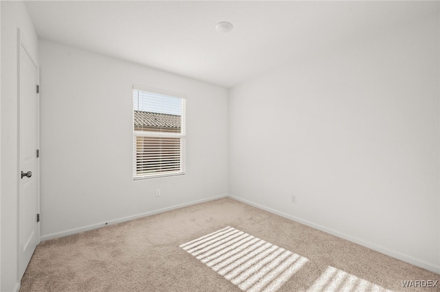 carpeted spare room featuring baseboards