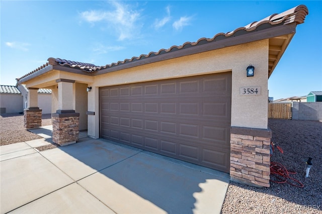 view of front of house with driveway, an attached garage, fence, and stucco siding