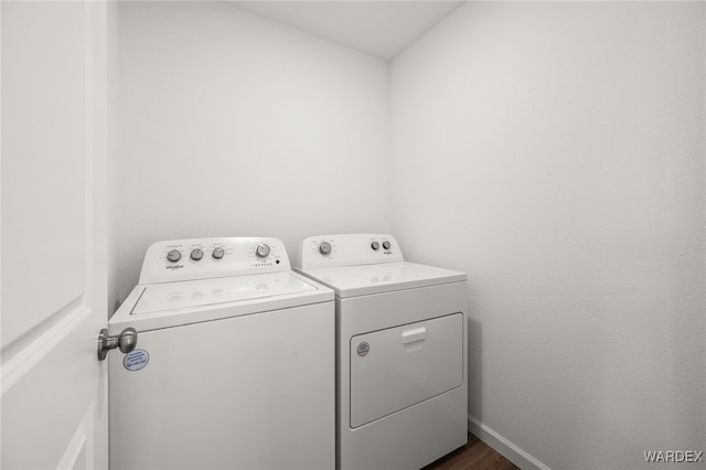 clothes washing area featuring laundry area, dark wood-type flooring, washer and clothes dryer, and baseboards