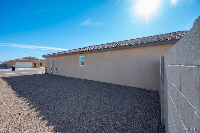 view of side of property with a tile roof and stucco siding