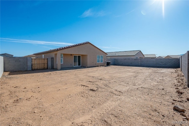 back of house with stucco siding, a gate, a fenced backyard, and central AC unit