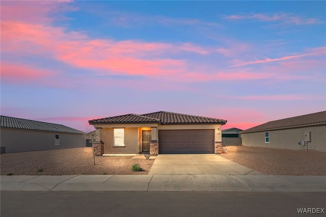 view of front of house featuring a garage, driveway, a tiled roof, and stucco siding