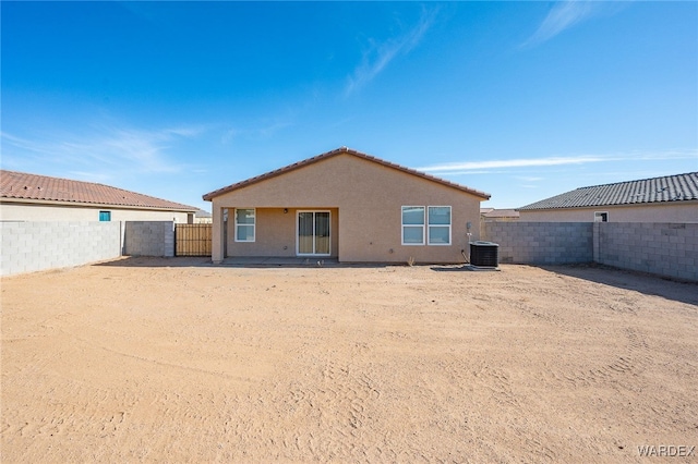 back of house with stucco siding, a fenced backyard, and central air condition unit