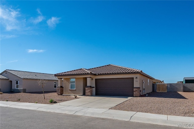 view of front facade with driveway, a tiled roof, an attached garage, fence, and stucco siding