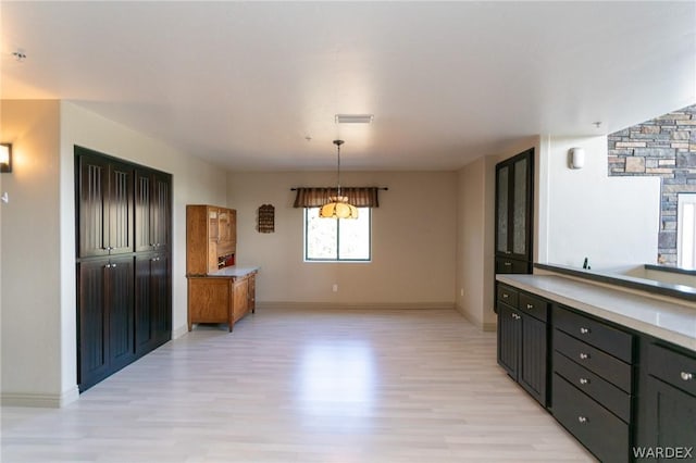 kitchen featuring pendant lighting, light countertops, visible vents, and light wood finished floors