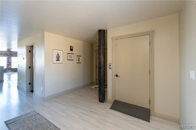 hallway featuring light wood-style flooring and baseboards