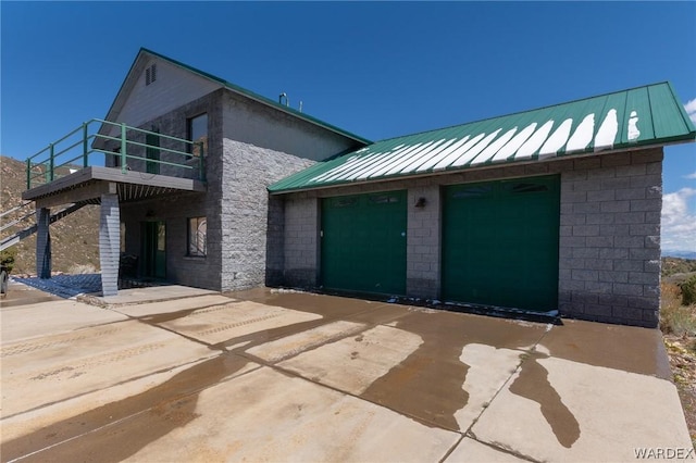 view of front of property featuring a balcony, a standing seam roof, driveway, and metal roof