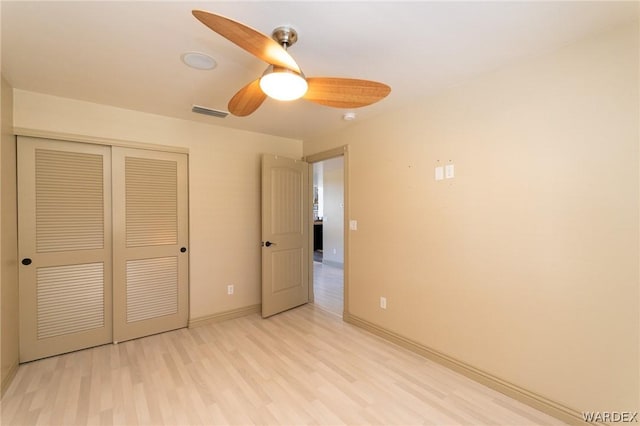 unfurnished bedroom featuring ceiling fan, light wood-style flooring, visible vents, baseboards, and a closet