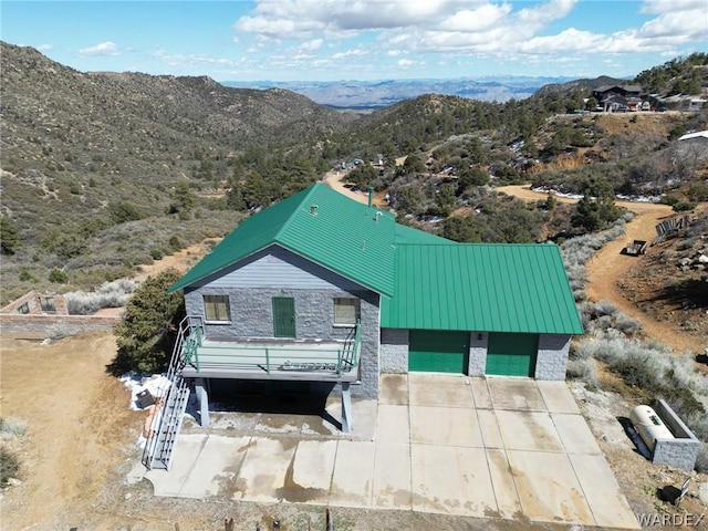 view of front of house with a garage, stone siding, a mountain view, and metal roof