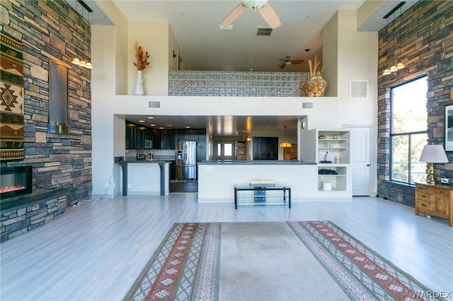 unfurnished living room featuring a high ceiling, visible vents, and a stone fireplace