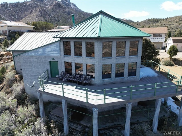 back of property featuring a deck with mountain view, metal roof, and a standing seam roof