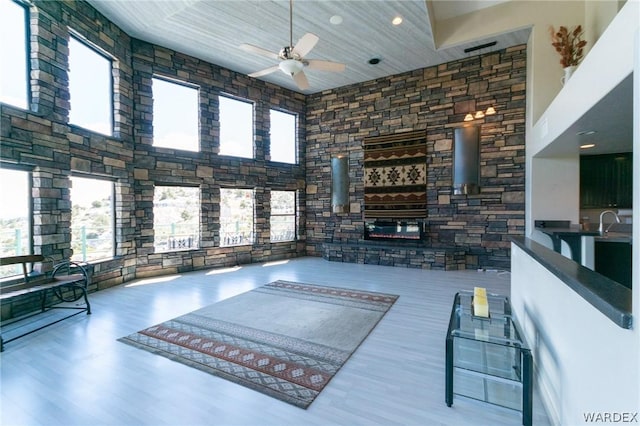 living area with a healthy amount of sunlight, ceiling fan, and a high ceiling