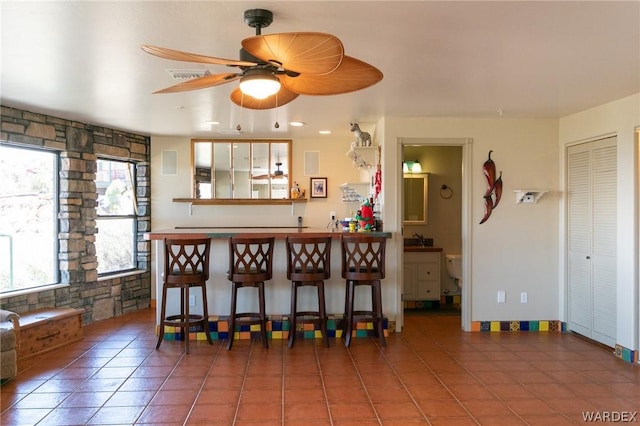 interior space featuring ceiling fan, bar, and tile patterned floors