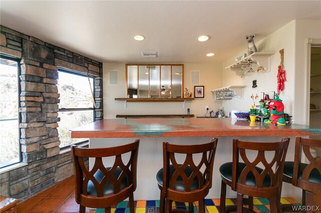 kitchen featuring tile patterned floors, a kitchen bar, visible vents, and recessed lighting