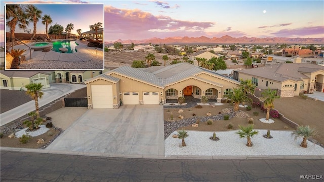 mediterranean / spanish-style house with a garage, a residential view, concrete driveway, and stucco siding