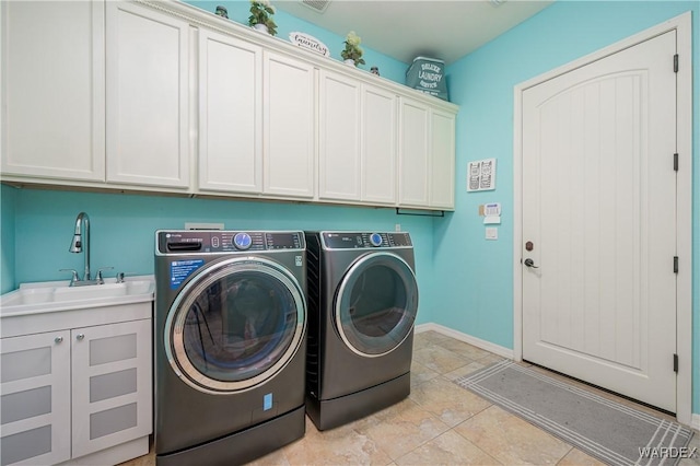 washroom featuring cabinet space, baseboards, separate washer and dryer, and a sink