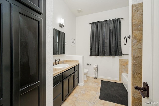 bathroom with toilet, vanity, a tub, baseboards, and tile patterned floors