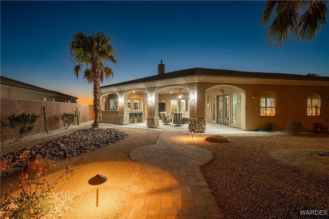 back of house featuring a fenced backyard, a chimney, french doors, a patio area, and stucco siding