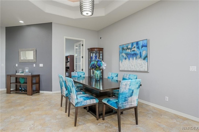 dining room with a tray ceiling, baseboards, and recessed lighting