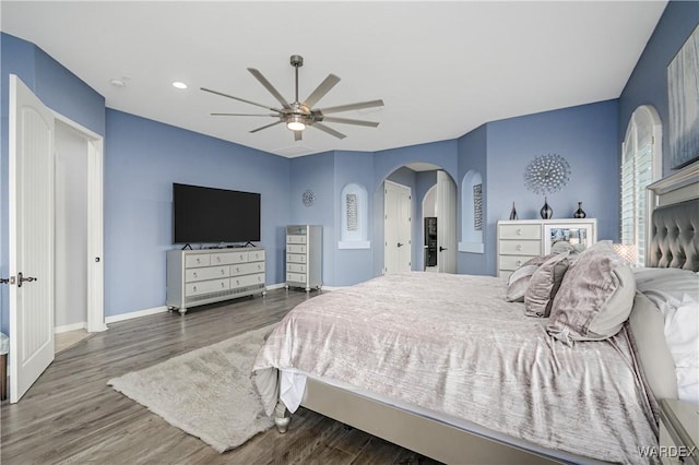 bedroom featuring baseboards, arched walkways, ceiling fan, and dark wood-type flooring