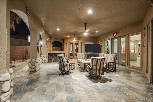 view of patio featuring french doors, ceiling fan, fence, an outdoor bar, and a fire pit