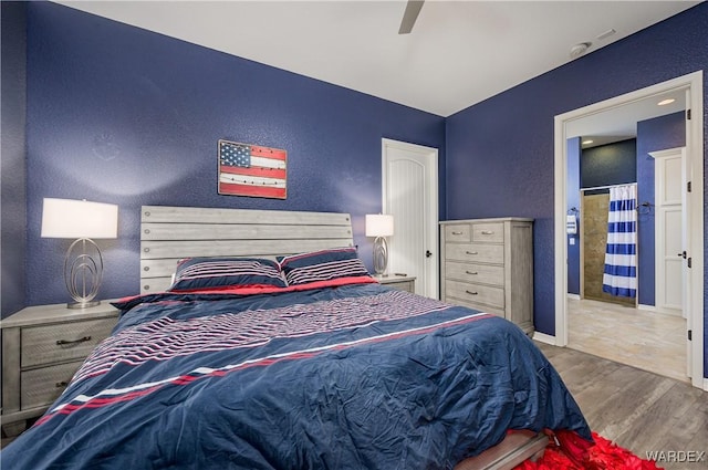 bedroom with ceiling fan, a textured wall, wood finished floors, and baseboards