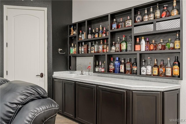 bar featuring a textured wall, wet bar, and a sink