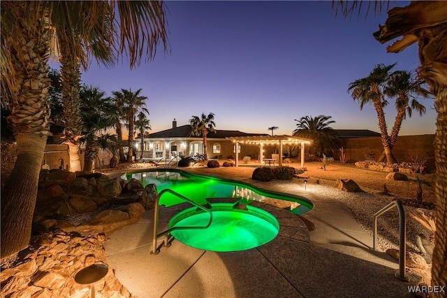 view of pool with a pool with connected hot tub, a patio area, fence, and a pergola