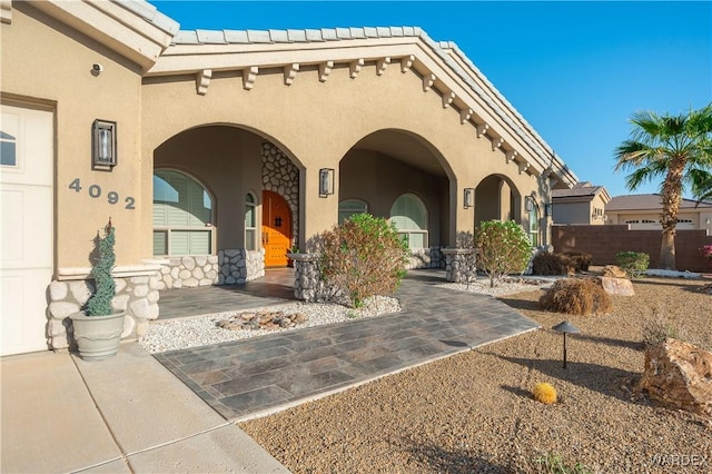 entrance to property featuring a tiled roof and stucco siding