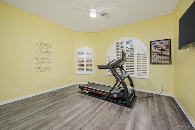 exercise area featuring baseboards, wood finished floors, visible vents, and a ceiling fan